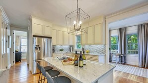 A modern kitchen with a central island, stainless steel appliances, and a geometric pendant light.