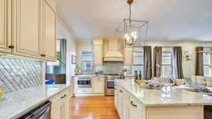 A spacious kitchen with a central island, built-in appliances, and a modern pendant light.