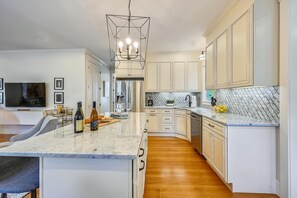 Una cocina moderna con encimeras de mármol, una isla central y un refrigerador empotrado.