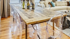 A modern living room with a wooden dining table, clear plastic chairs, a white sofa, and a bull skull decoration. - 15BR Boston Entire Building | 3 Living Spaces (Boston)