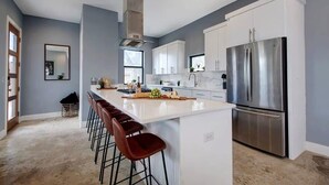 A modern kitchen with a central island, stainless steel appliances, and bar stools.