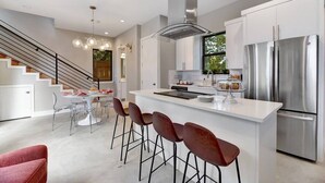 A modern kitchen with a central island, stainless steel appliances, and a staircase leading to another level.