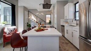 A modern kitchen with a central island, stainless steel appliances, and a staircase leading to an upper level.