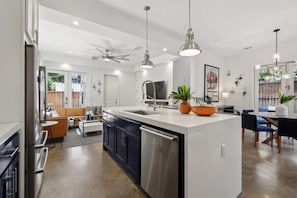Uma cozinha moderna com ilha central, eletrodomésticos de aço inoxidável e iluminação pendente.
