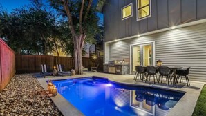 A backyard with a swimming pool, patio furniture, and a wooden fence. - Luxe 5BR East Austin Home | Private Pool & Balcony (Austin)