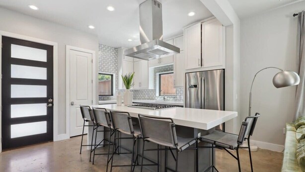 A modern kitchen with a central island, stainless steel appliances, and bar-style seating. - Luxe 5BR East Austin Home | Private Pool & Balcony (Austin)