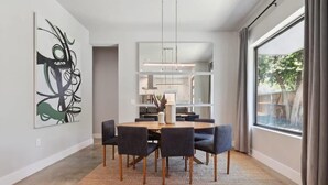 A modern dining area with a round table, dark chairs, and a woven rug. - Luxe 5BR East Austin Home | Private Pool & Balcony (Austin)