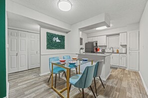 Eine moderne Küche mit weißen Schränken, einer Glasinsel und einer Wanddekoration in Grün.