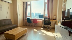 Un salon moderne avec un canapé, une table basse en bois, un bureau avec un ordinateur et un téléviseur.