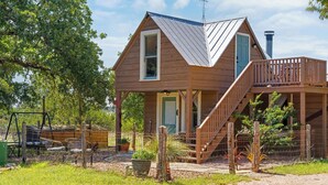 Une cabane en bois dotée d’un balcon et d’un escalier menant à une terrasse.