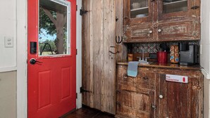 Une porte rouge avec une fenêtre, des armoires en bois dotées de portes en verre et un panneau indiquant la présence d’un extincteur.