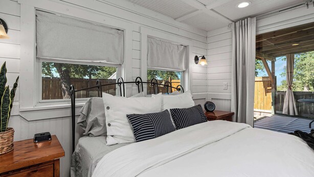 Une chambre à coucher avec un lit, des murs blancs et une fenêtre avec des stores.