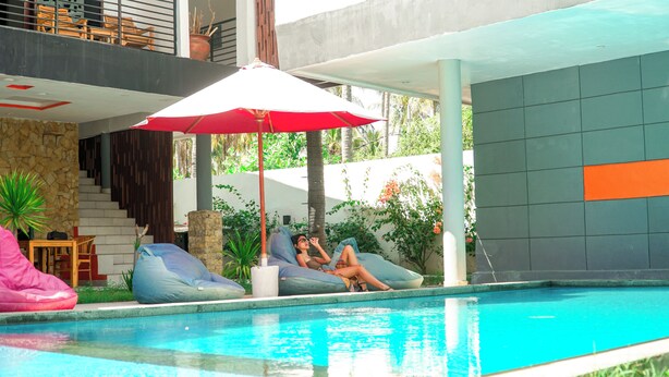 Un área de piscina con dos sillas de descanso y una sombrilla roja.