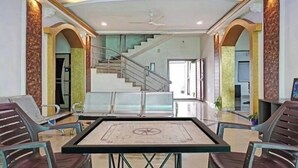 A spacious lobby with a central table, a staircase, and seating areas. - The Gren Villa Valley View (Mahabaleshwar)