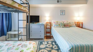 Habitación con literas, escritorio, televisión y cama con colcha a rayas.