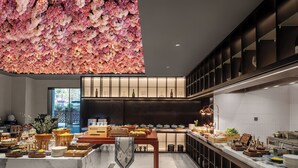 Une cuisine moderne dotée d’un îlot central, de meubles de couleur sombre et d’une composition florale décorative placée au-dessus.