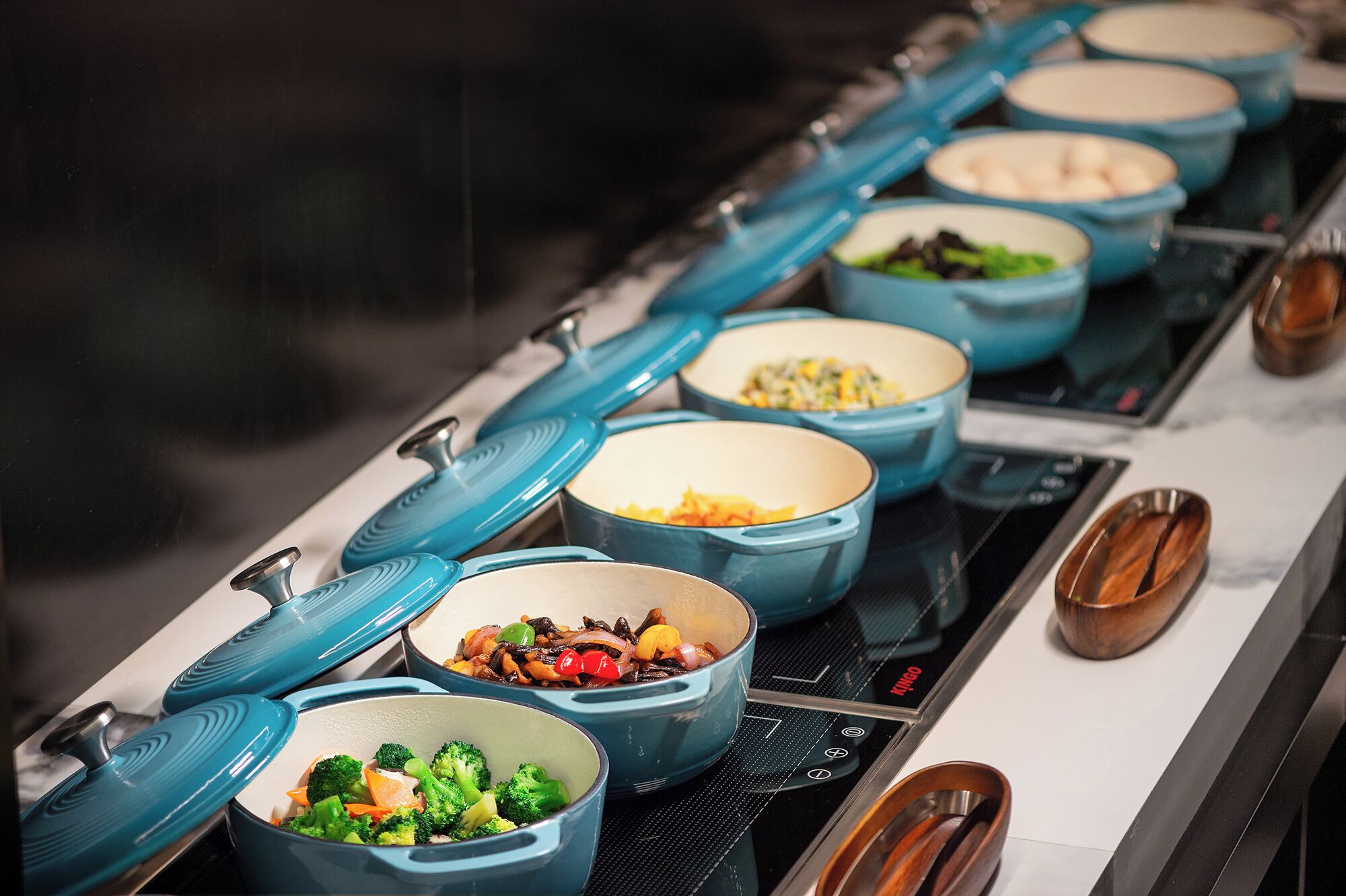 A buffet line with various dishes in blue bowls on a stove.