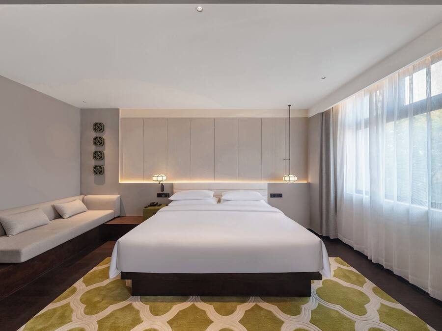 Una habitación de hotel moderna con una cama grande, un sofá y un escritorio.