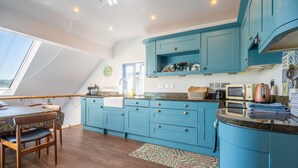 Une cuisine avec des meubles de rangement bleus, un plancher en bois et un coin repas comprenant une table et des chaises.