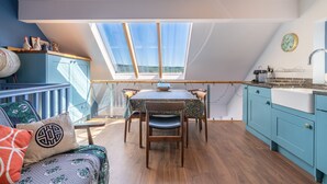 Une pièce de style loft avec une lucarne, un plancher en bois, une table à manger avec des chaises et un coin cuisine.