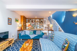 A living room with a sofa, coffee table, and bookshelves. - Linstead House -  Modern Townhouse with views (Kendal)