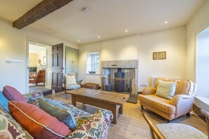 A cozy living room with a fireplace, a sofa, a chair, and a wooden coffee table.