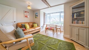 Un salon moderne avec un canapé, un fauteuil et un coin repas.