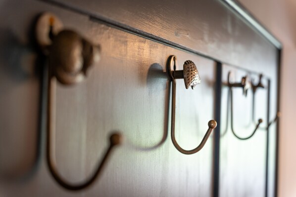 A close-up of a wall-mounted coat rack with hooks and a decorative knob.