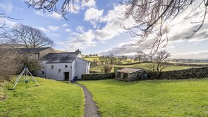 A rural property with a white house, a stone wall, and a grassy path leading to the house. - Drawell Cottage -  Cottage on a working farm with splendid views (Sedbergh)