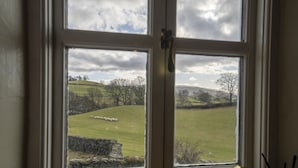 A window with a view of a green field and a stone wall. - Drawell Cottage -  Cottage on a working farm with splendid views (Sedbergh)
