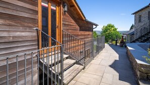 Un bâtiment en bois doté d’un balcon, d’un escalier en pierre et d’un mur en pierre.