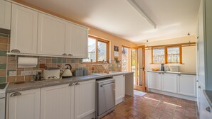 Une cuisine avec des meubles blancs, un lave-vaisselle, un grille-pain et un évier.