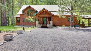 Une grande cabane en rondins dotée d’un porche avant bien visible, de nombreuses fenêtres et d’une allée en gravier.