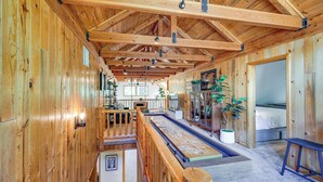 Un intérieur spacieux en bois, avec un plafond haut, une longue table à manger et un coin salon confortable.