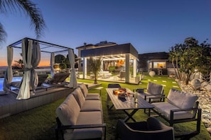 Ein moderner Außenbereich mit Pool, Sitzgelegenheiten und einer überdachten Terrasse.