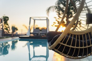 Una sedia in vimini vicino a una piscina con vista sul tramonto.