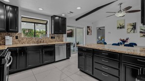 A modern kitchen with dark cabinets, granite countertops, and stainless steel appliances. - Vibrant Home & Sparkling Pool. Entertain in Luxury at this Desert Gem! #75-354 (Bermuda Dunes)