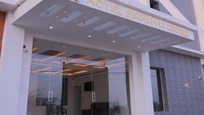A modern hotel entrance with a glass facade, a name sign, and a green mat at the entrance. - Hotel Sahaya Arasi (Kanyakumari)