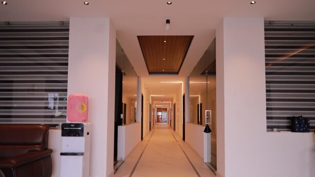 A modern hotel lobby with a central corridor, a reception desk, and a seating area with a brown sofa. - Hotel Sahaya Arasi (Kanyakumari)