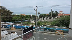 A balcony with a view of a street, power lines, and distant buildings. - Hotel Sahaya Arasi (Kanyakumari)
