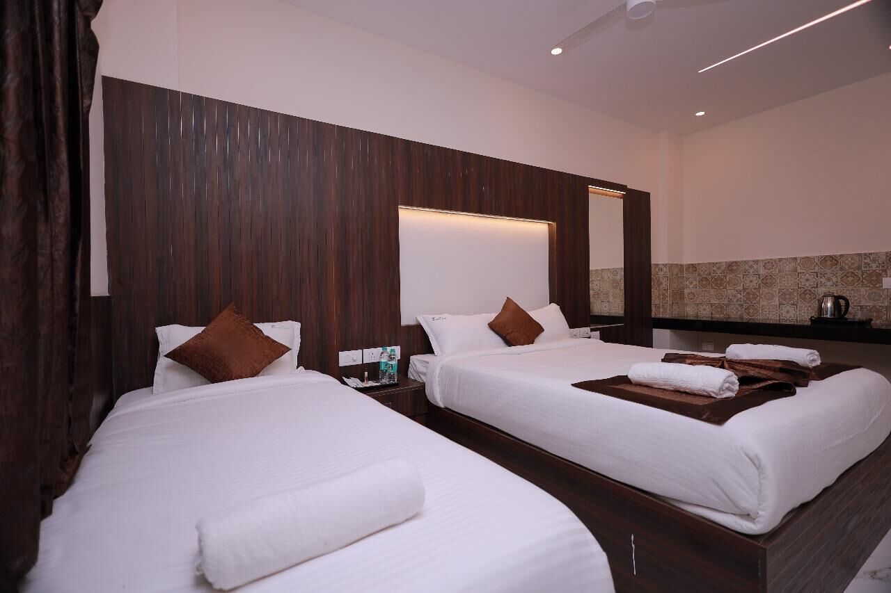 A hotel room with two beds, a wooden headboard, a large mirror, and a minibar.
