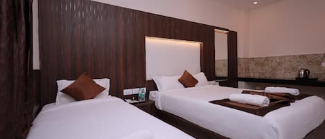 A hotel room with two beds, a wooden headboard, a large mirror, and a minibar.