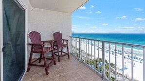 Un balcon avec deux fauteuils Adirondack, une vue sur la plage et un ciel dégagé.