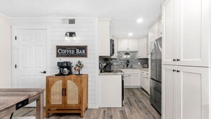 Une cuisine moderne avec des meubles blancs, un panneau indiquant un coin café et un buffet en bois.