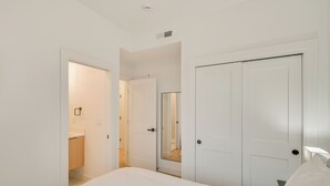 A bedroom with a bed, a wardrobe, a mirror, and a bathroom visible through an open door.