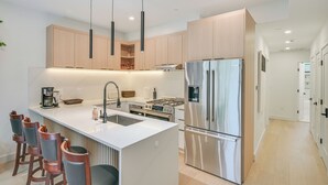 A modern kitchen with a central island, stainless steel appliances, and pendant lighting.