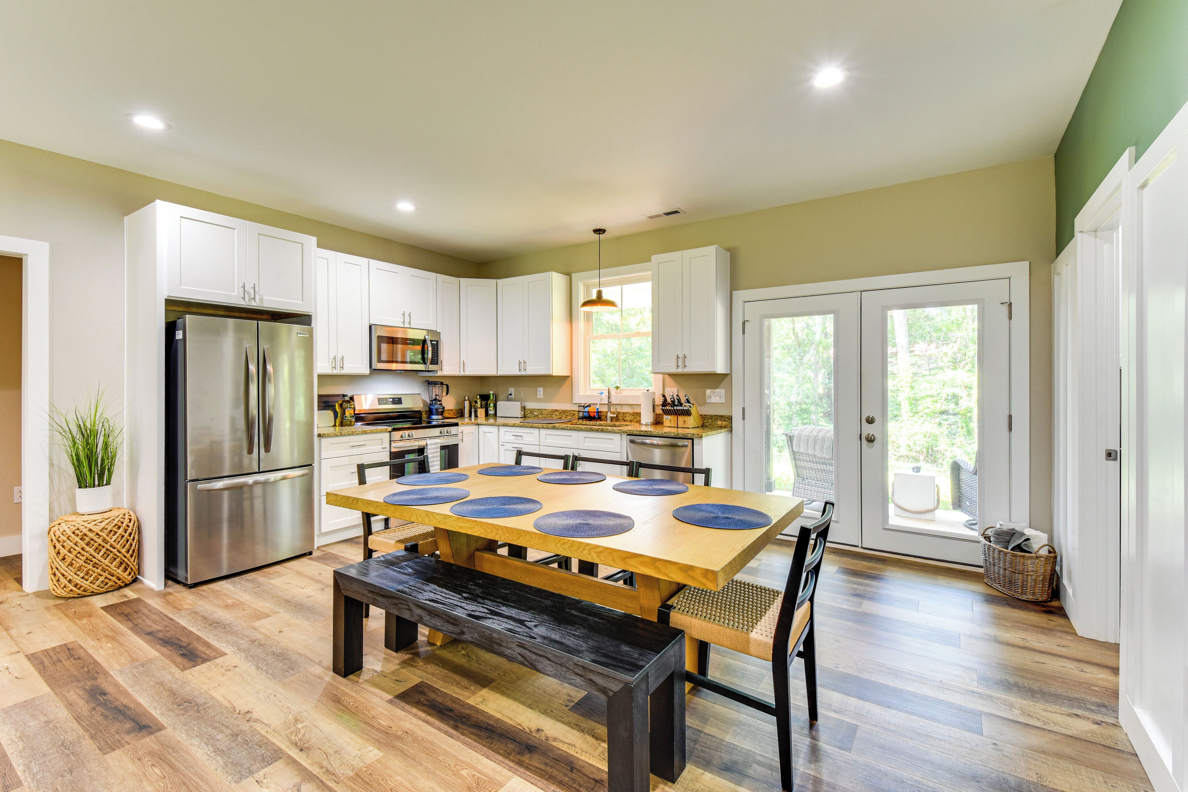 A modern kitchen with a large island, stainless steel appliances, and a dining area with a bench.