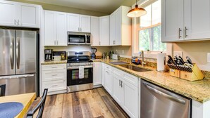 A modern kitchen with white cabinets, stainless steel appliances, and a granite countertop. - 1 Mi to Lake Hartwell: Updated Retreat w/ Patio! (Anderson)