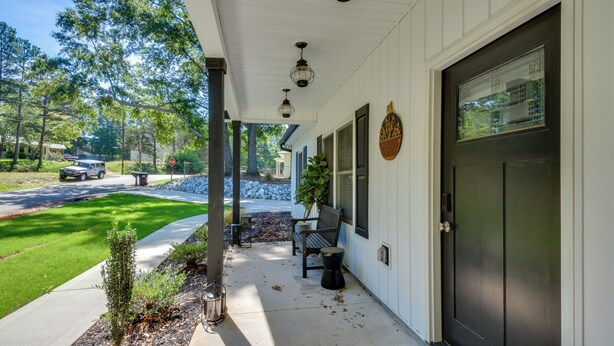 A house with a porch, a black door, and a small garden. - 1 Mi to Lake Hartwell: Updated Retreat w/ Patio! (Anderson)