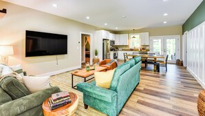 A spacious living room with a green sofa, a coffee table, and a flat-screen TV mounted on the wall. - 1 Mi to Lake Hartwell: Updated Retreat w/ Patio! (Anderson)